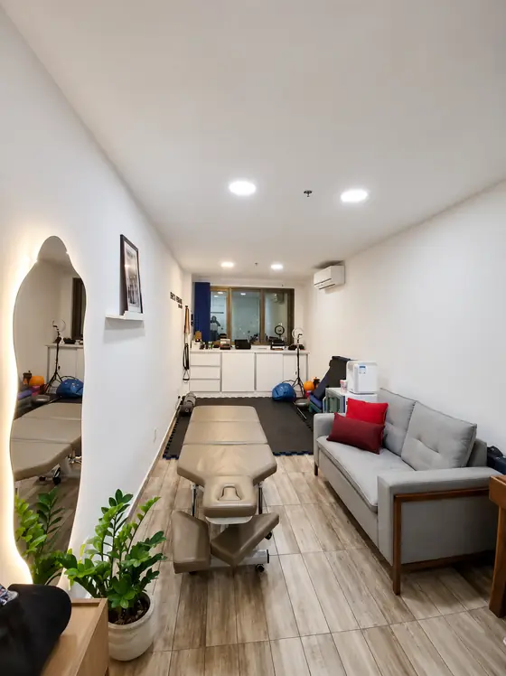 Sala ampla com maca de quiropraxia, tatame e acessórios de exercício terapêutico